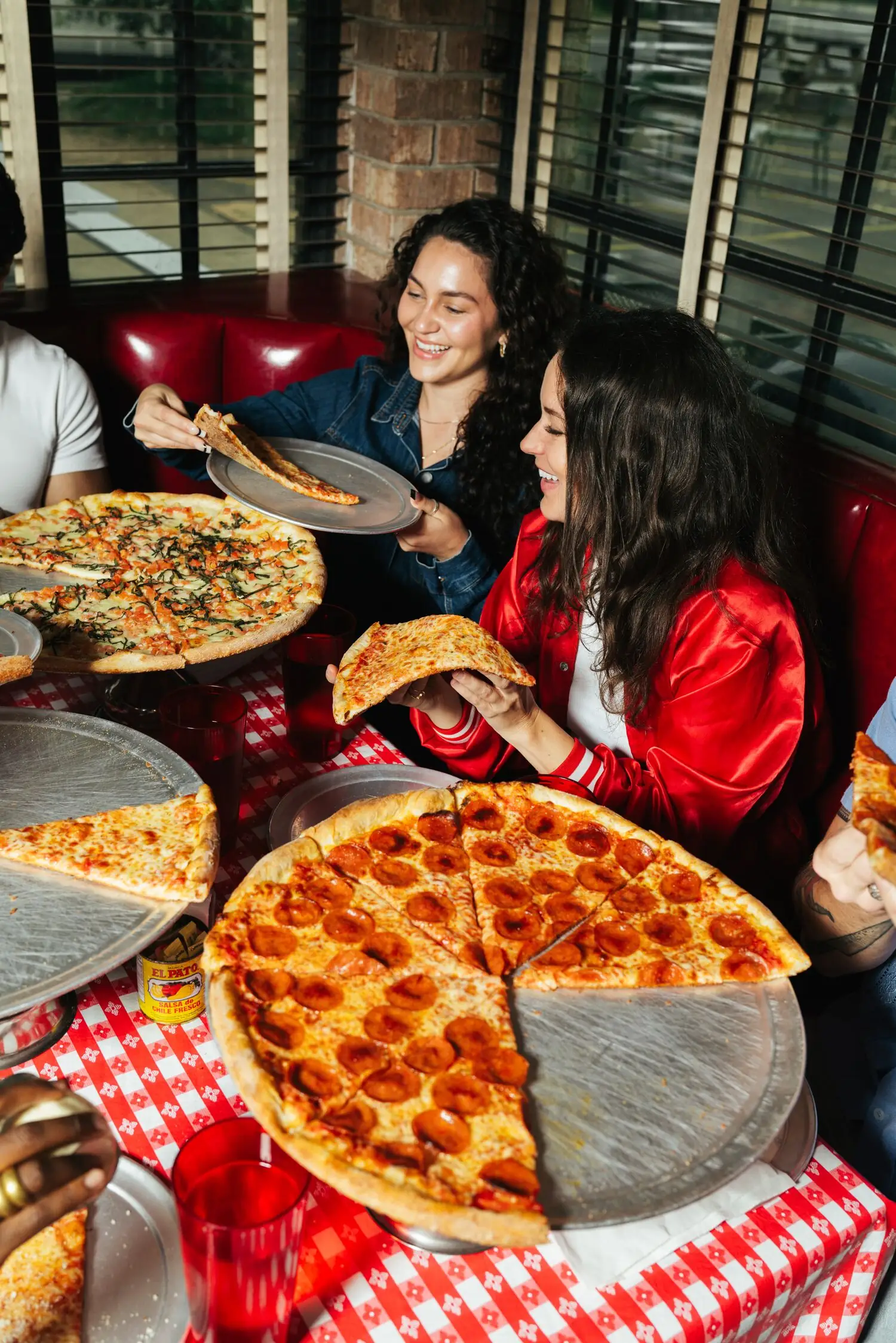 Friends sharing pizzas in a vinyl booth