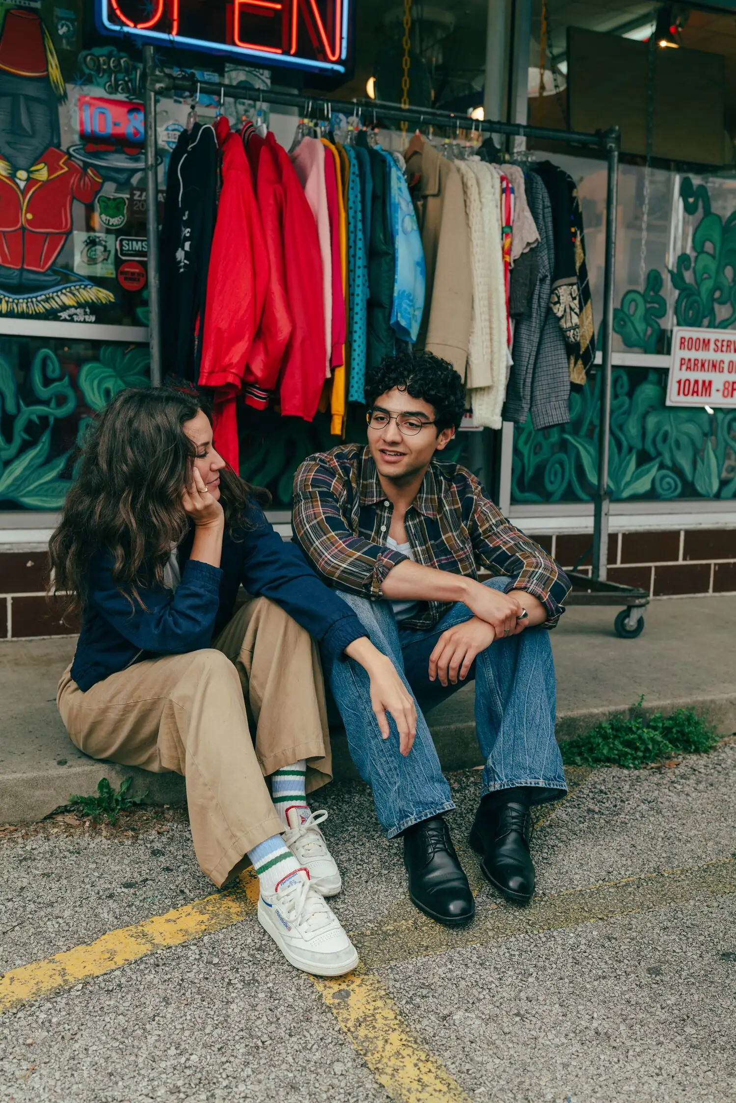 A couple sits curbside outside Room Service Vintage
